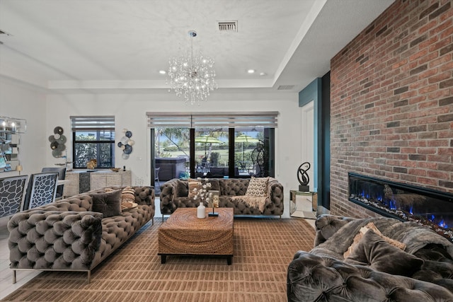 living area with a chandelier, recessed lighting, a fireplace, visible vents, and a raised ceiling