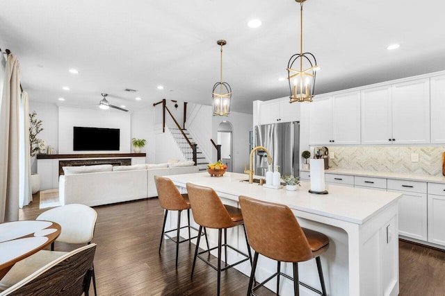 kitchen with dark wood-type flooring, tasteful backsplash, white cabinetry, arched walkways, and stainless steel fridge with ice dispenser