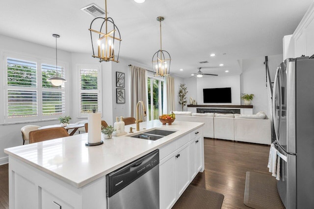 kitchen with visible vents, a sink, an island with sink, stainless steel appliances, and dark wood-style flooring