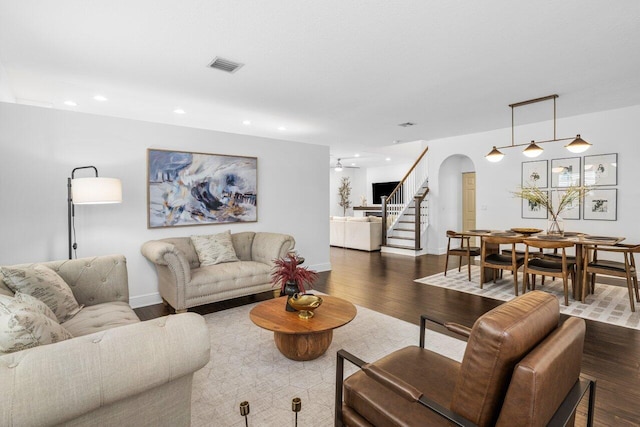 living room with visible vents, recessed lighting, stairway, arched walkways, and dark wood-style flooring