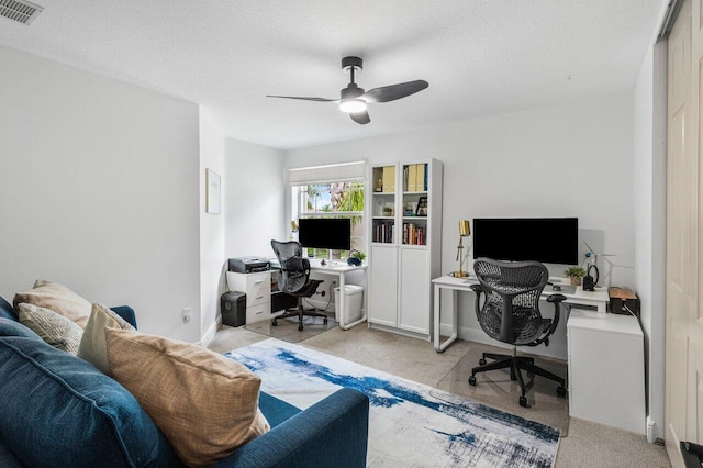 carpeted home office with visible vents, a textured ceiling, and a ceiling fan