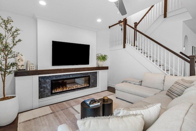 living room featuring stairway, wood finished floors, a premium fireplace, recessed lighting, and ceiling fan