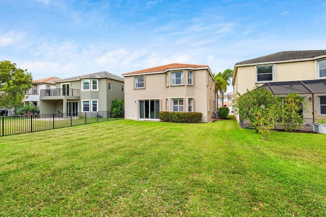 back of house featuring a lawn, fence, a residential view, and stucco siding