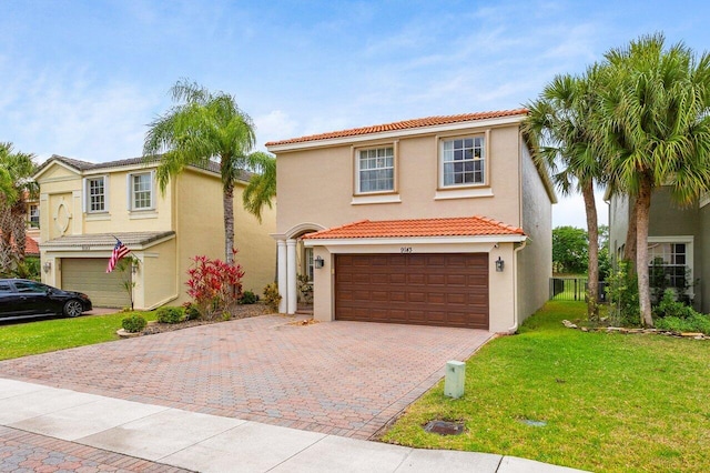 mediterranean / spanish-style house with stucco siding, a tile roof, and decorative driveway