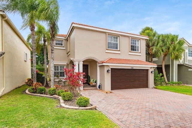 mediterranean / spanish house featuring a tile roof, decorative driveway, a garage, and stucco siding