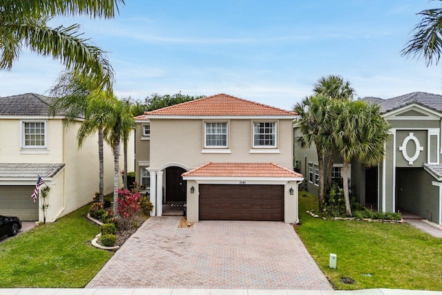 mediterranean / spanish-style house with a front yard, stucco siding, a garage, a tile roof, and decorative driveway