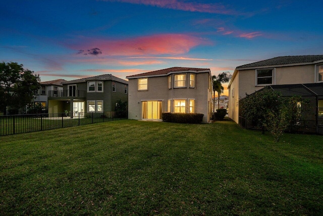 rear view of property featuring stucco siding, a lawn, and a fenced backyard