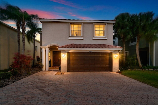 view of front of house featuring a tile roof, decorative driveway, a garage, and stucco siding