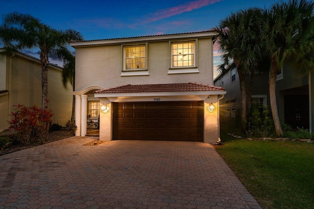 view of front of property with a tiled roof, decorative driveway, a garage, and stucco siding