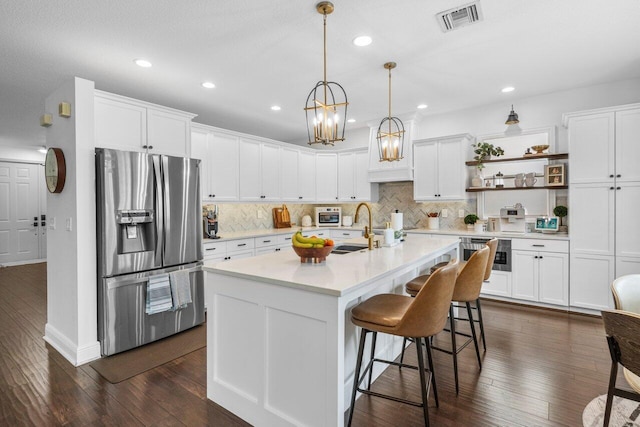 kitchen with backsplash, dark wood finished floors, stainless steel appliances, arched walkways, and light countertops