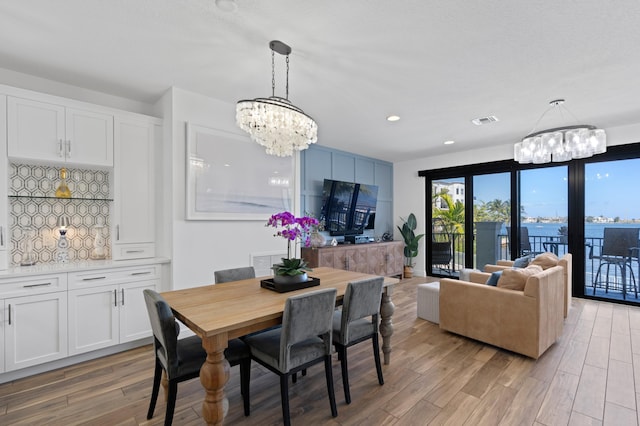 dining space with light wood-type flooring, visible vents, a notable chandelier, and recessed lighting