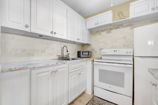 kitchen featuring white appliances, backsplash, a sink, and white cabinetry