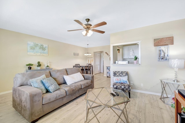 living area featuring ceiling fan, baseboards, and wood finished floors