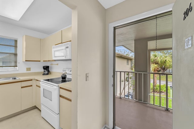 kitchen with white appliances, light countertops, a sink, and cream cabinets