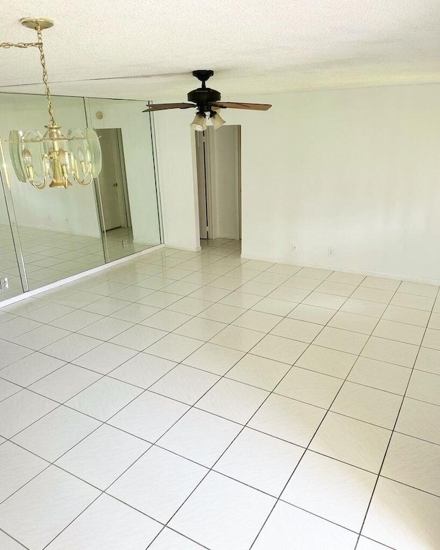 spare room with light tile patterned flooring, a textured ceiling, and ceiling fan with notable chandelier