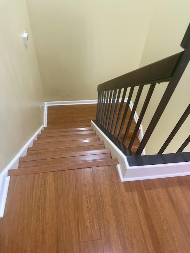 stairway with baseboards and wood finished floors