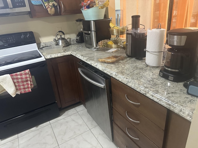 kitchen featuring dark brown cabinetry, marble finish floor, appliances with stainless steel finishes, and light stone countertops