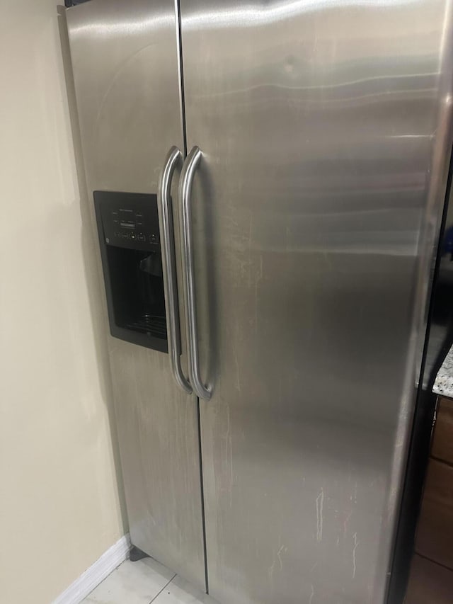 interior details with baseboards and stainless steel fridge with ice dispenser