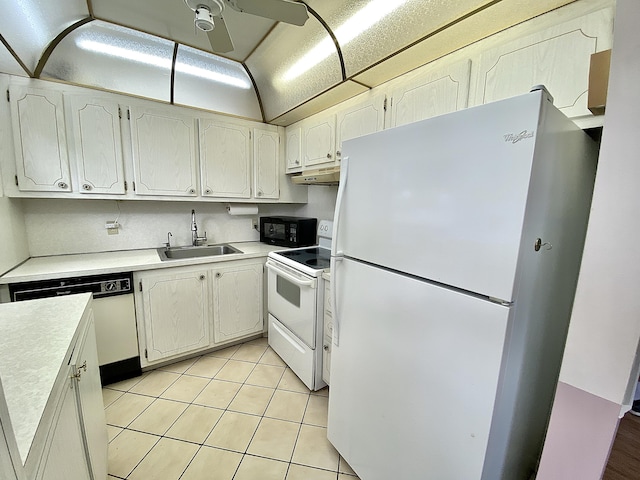 kitchen with light tile patterned flooring, under cabinet range hood, white appliances, a sink, and light countertops