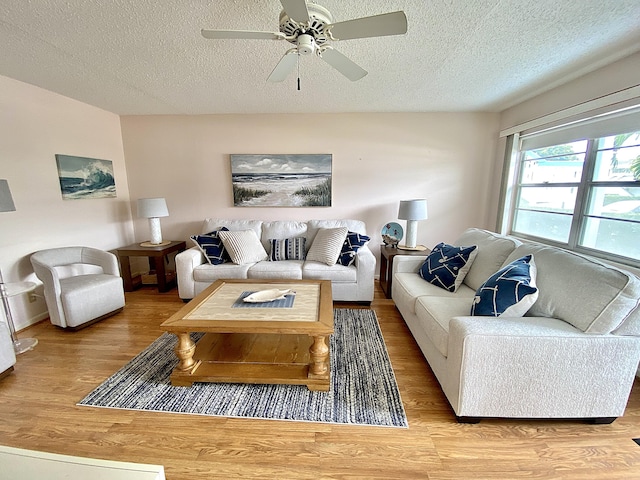 living room featuring a ceiling fan, a textured ceiling, and wood finished floors