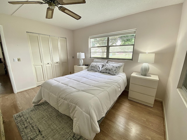 bedroom featuring baseboards, ceiling fan, wood finished floors, a textured ceiling, and a closet