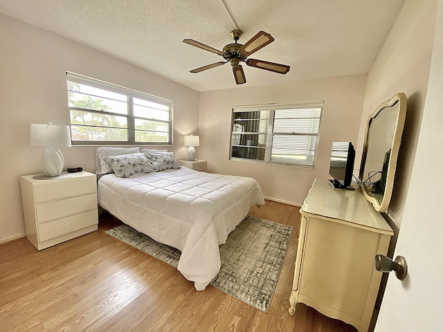 bedroom featuring light wood-type flooring, ceiling fan, and a textured ceiling