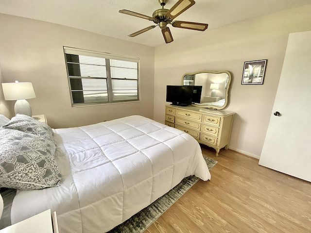 bedroom featuring ceiling fan, baseboards, and light wood-style floors