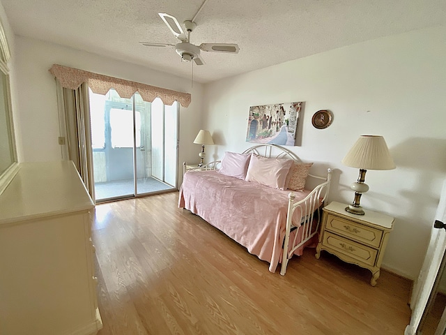 bedroom featuring light wood-type flooring, access to exterior, a ceiling fan, and a textured ceiling