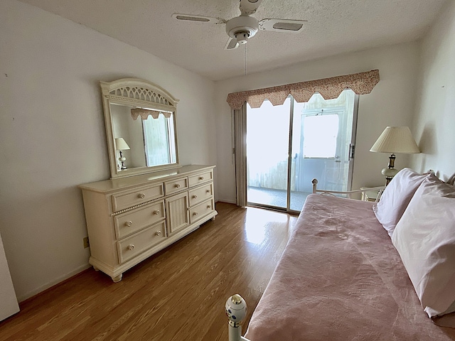 bedroom with a ceiling fan, access to outside, a textured ceiling, and wood finished floors