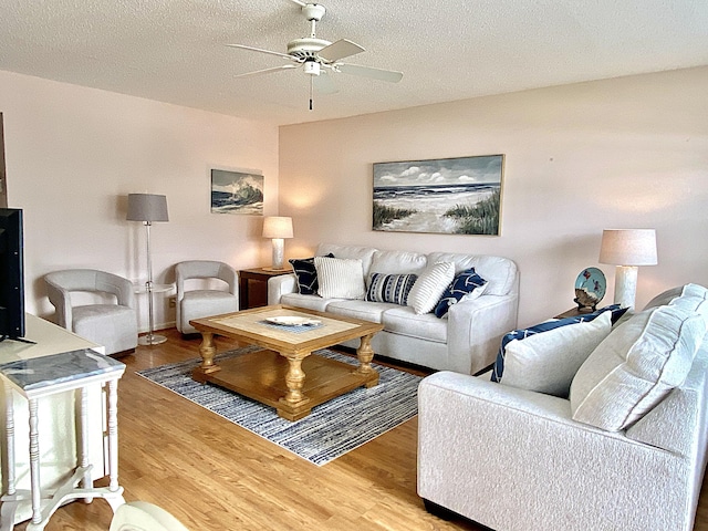 living room featuring ceiling fan, a textured ceiling, and wood finished floors