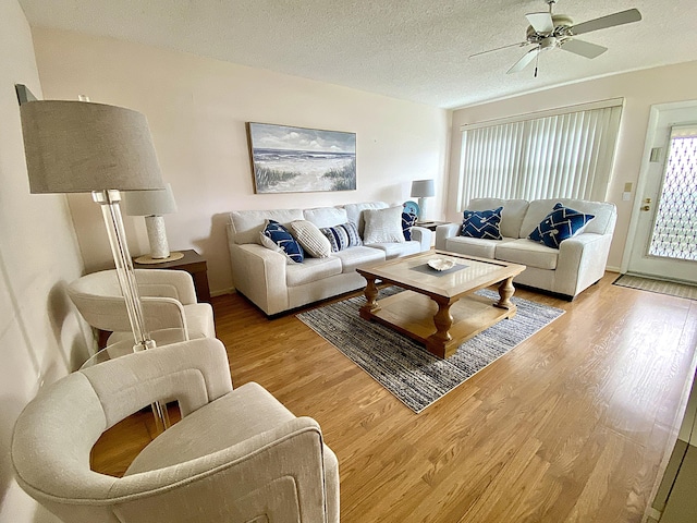 living room featuring a textured ceiling, light wood-type flooring, and a ceiling fan