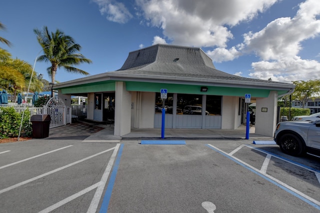 view of building exterior with uncovered parking and fence