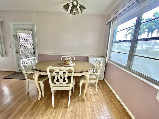 dining room with light wood finished floors, baseboards, and a ceiling fan