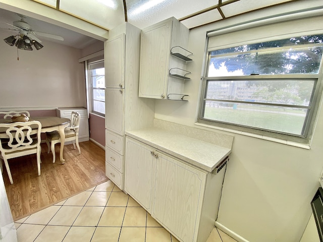 kitchen with light tile patterned floors, light countertops, open shelves, and a ceiling fan