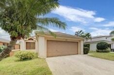 view of front of home with a front yard, an attached garage, and driveway