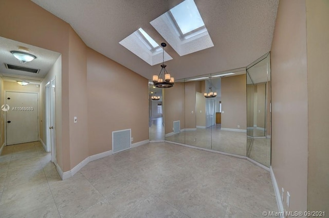 spare room with visible vents, vaulted ceiling with skylight, and baseboards