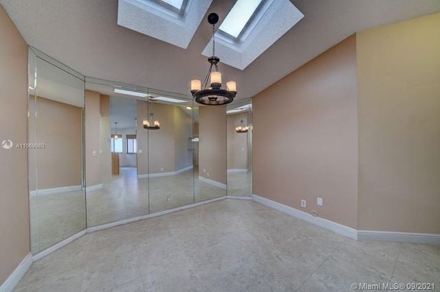 unfurnished room with an inviting chandelier, a skylight, and baseboards