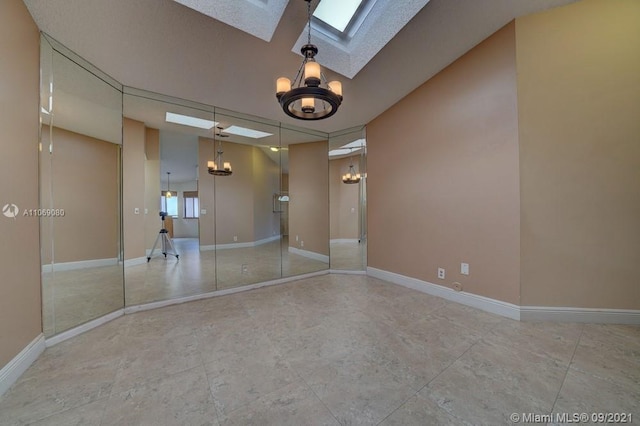 unfurnished room with an inviting chandelier, a skylight, and baseboards