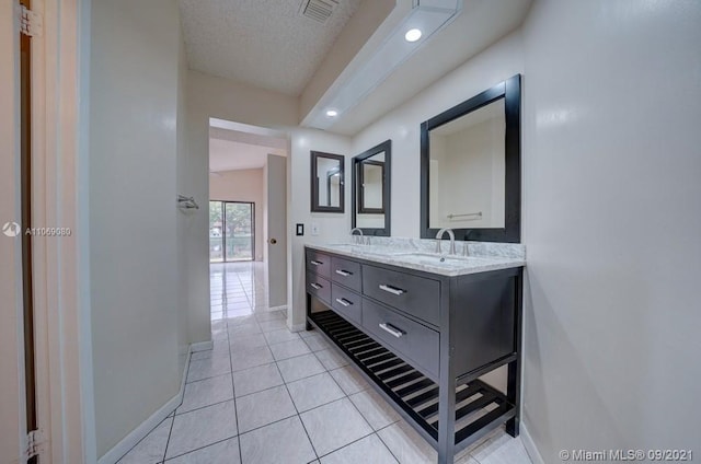 full bathroom with visible vents, a textured ceiling, tile patterned flooring, double vanity, and baseboards