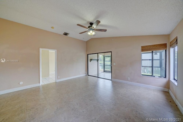 empty room featuring lofted ceiling, baseboards, visible vents, and a textured ceiling