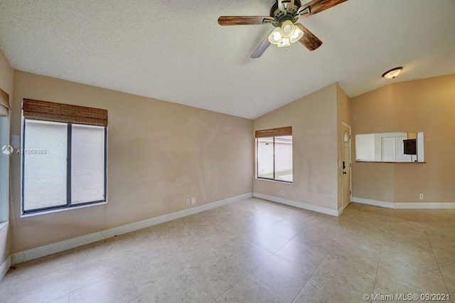 spare room featuring baseboards, a textured ceiling, a ceiling fan, and vaulted ceiling