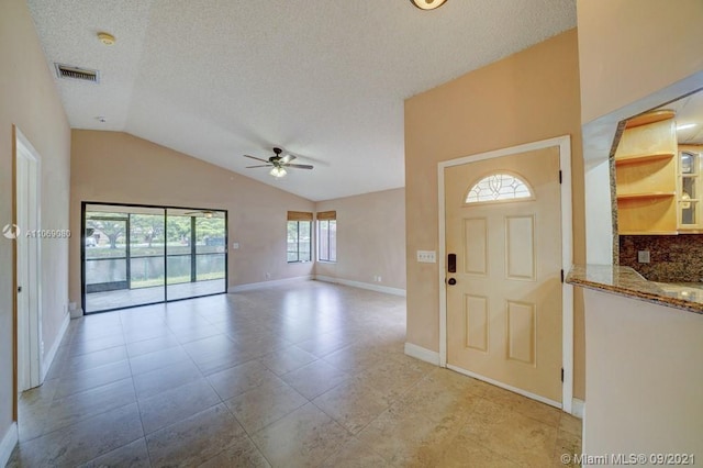 foyer with baseboards, visible vents, lofted ceiling, ceiling fan, and a textured ceiling