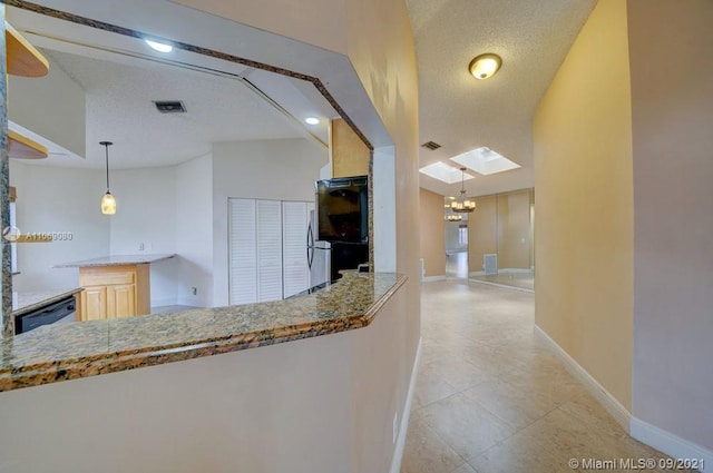 hallway with visible vents, a textured ceiling, and baseboards