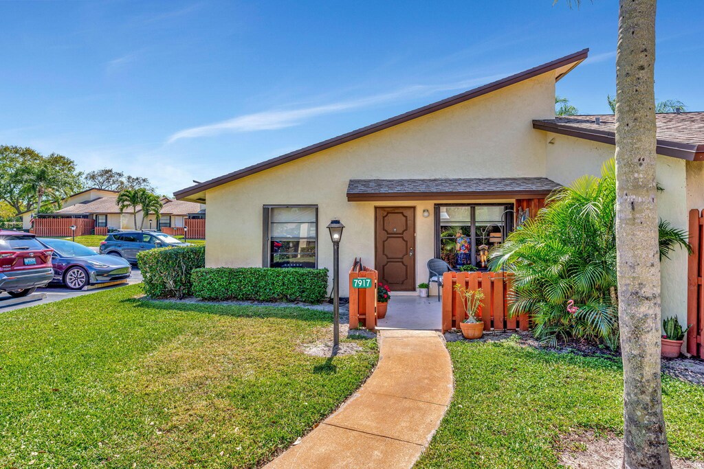 entrance to property featuring a yard and stucco siding