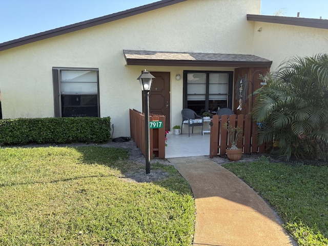 entrance to property featuring a yard and stucco siding