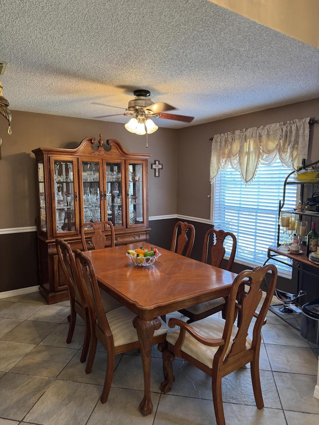 dining area featuring ceiling fan, a textured ceiling, and light tile patterned flooring