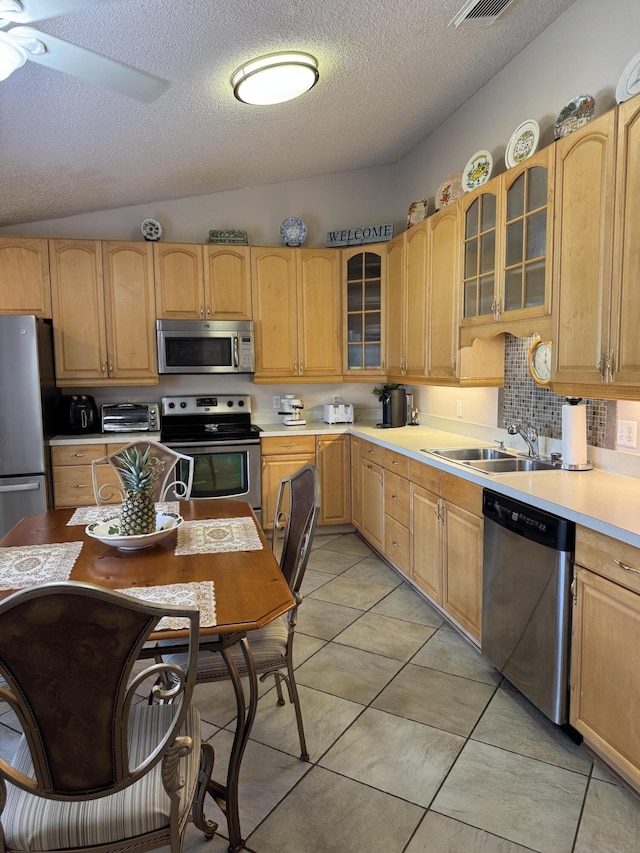 kitchen with ceiling fan, appliances with stainless steel finishes, light countertops, light brown cabinets, and a sink