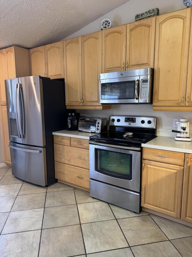 kitchen with appliances with stainless steel finishes, light countertops, a textured ceiling, and light brown cabinetry