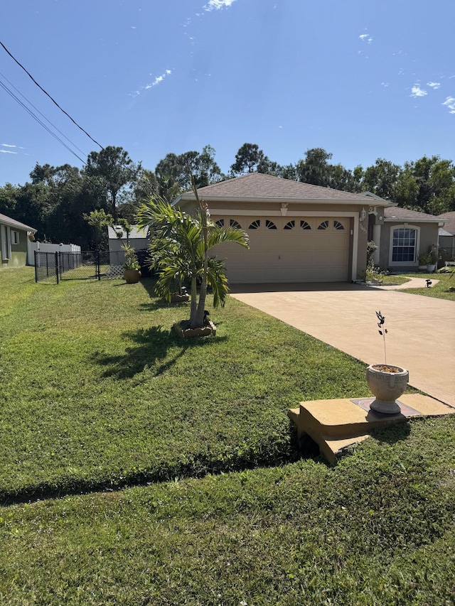 view of front of property featuring driveway, an attached garage, fence, a front yard, and stucco siding