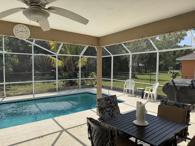 outdoor pool with glass enclosure, area for grilling, and a patio